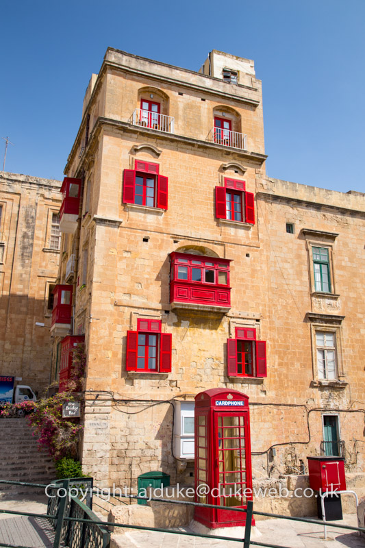 Valetta buildings scene showing characteristic Maltese balconies and British red phonebox, Malta